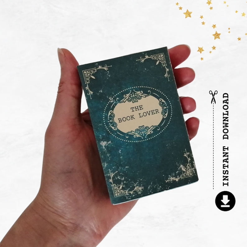 May include: A teal blue book with a vintage design and the text "The Book Lover" in a gold oval frame.