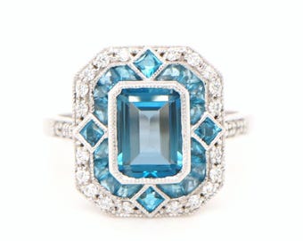 Anillo de cóctel con topacio azul Londres y halo de diamantes en oro blanco de 9 k.