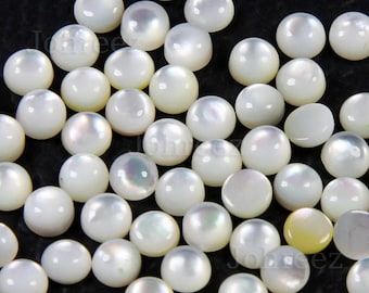 May include: A collection of white iridescent round cabochon gemstones. The gemstones are smooth and have a pearlescent sheen.
