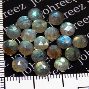 May include: A collection of 18 iridescent, faceted, round labradorite gemstones. The stones are a mix of gray, blue, and green hues.