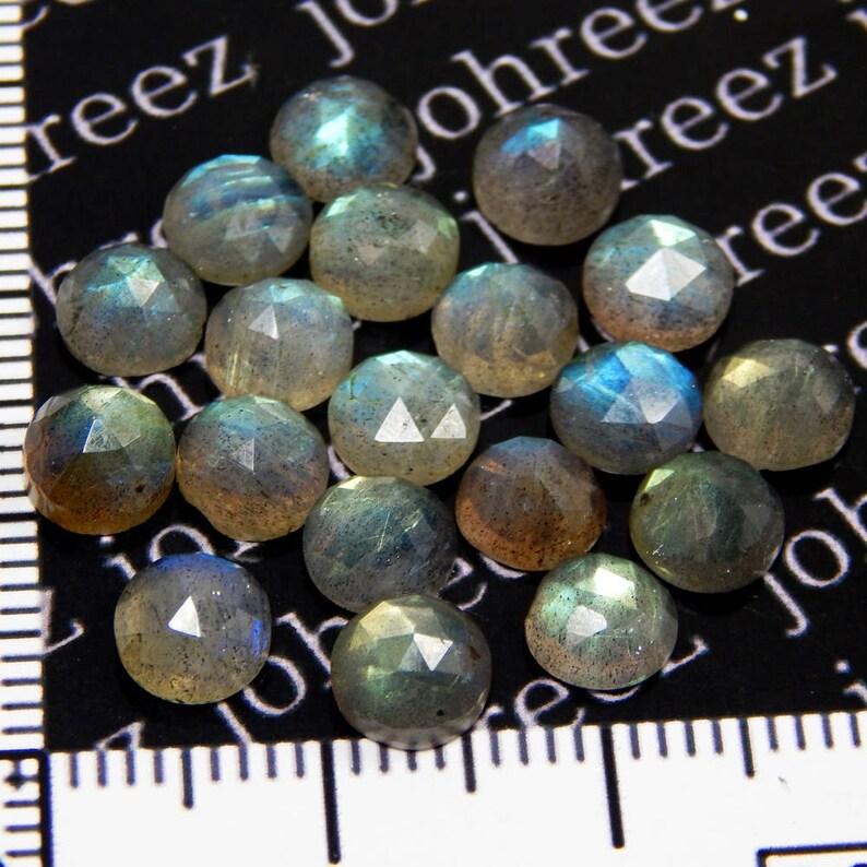 May include: A collection of 18 iridescent, faceted, round labradorite gemstones. The stones are a mix of gray, blue, and green hues.