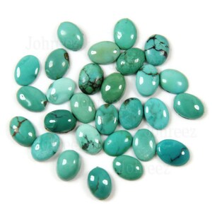 May include: A collection of oval-shaped turquoise stones in various shades of blue and green. The stones are smooth and polished, and they are arranged in a random pattern on a white background.
