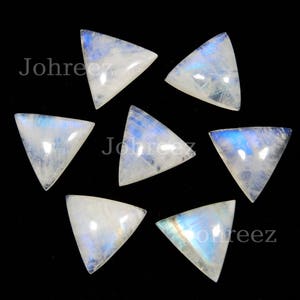 May include: Seven iridescent white triangular moonstone cabochons with a blue sheen. The stones are arranged in a circle on a black background.