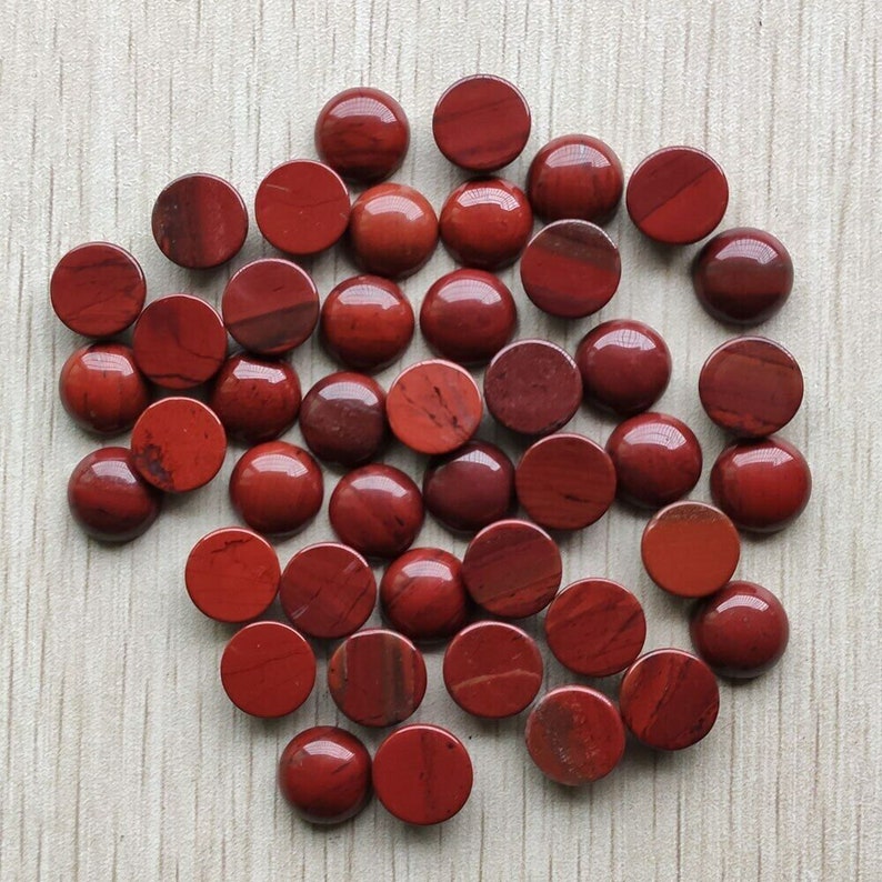 May include: A collection of 40 red jasper cabochons, each measuring approximately 12mm in diameter. The cabochons are smooth and polished, with a variety of red and brown hues.