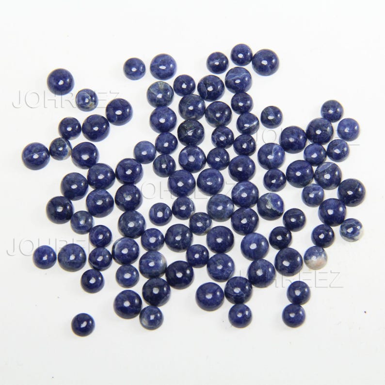 May include: A collection of round, blue gemstone cabochons. The cabochons are smooth and polished, with a slightly mottled appearance.