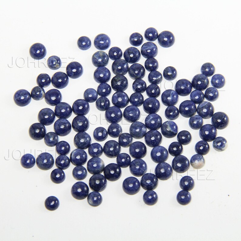 May include: A collection of round, blue gemstone cabochons. The cabochons are smooth and polished, with a slightly mottled appearance.