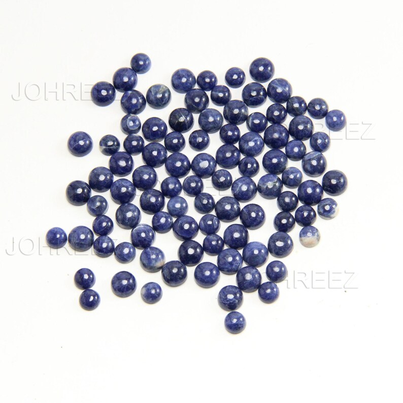 May include: A large group of round, blue gemstone cabochons. The cabochons are smooth and polished, with a slight variation in color.