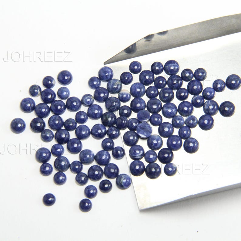 May include: A pile of round, blue gemstone cabochons. The cabochons are smooth and polished, with a slightly iridescent finish.
