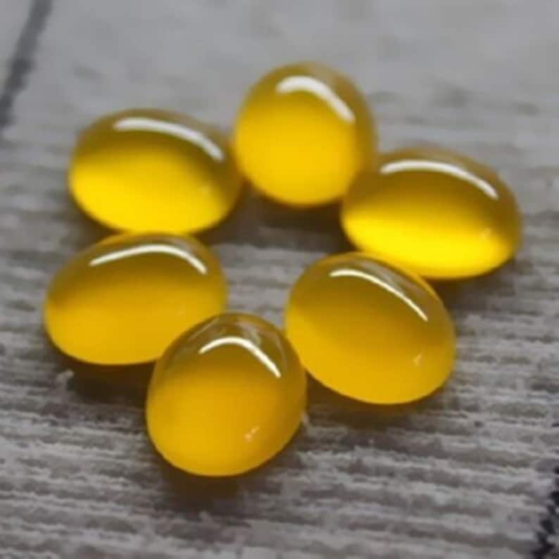 May include: Six smooth, oval-shaped yellow gemstones arranged in a circular pattern. Each stone features a polished, translucent surface with a high-gloss finish that reflects light, creating bright white highlights on their rounded tops.