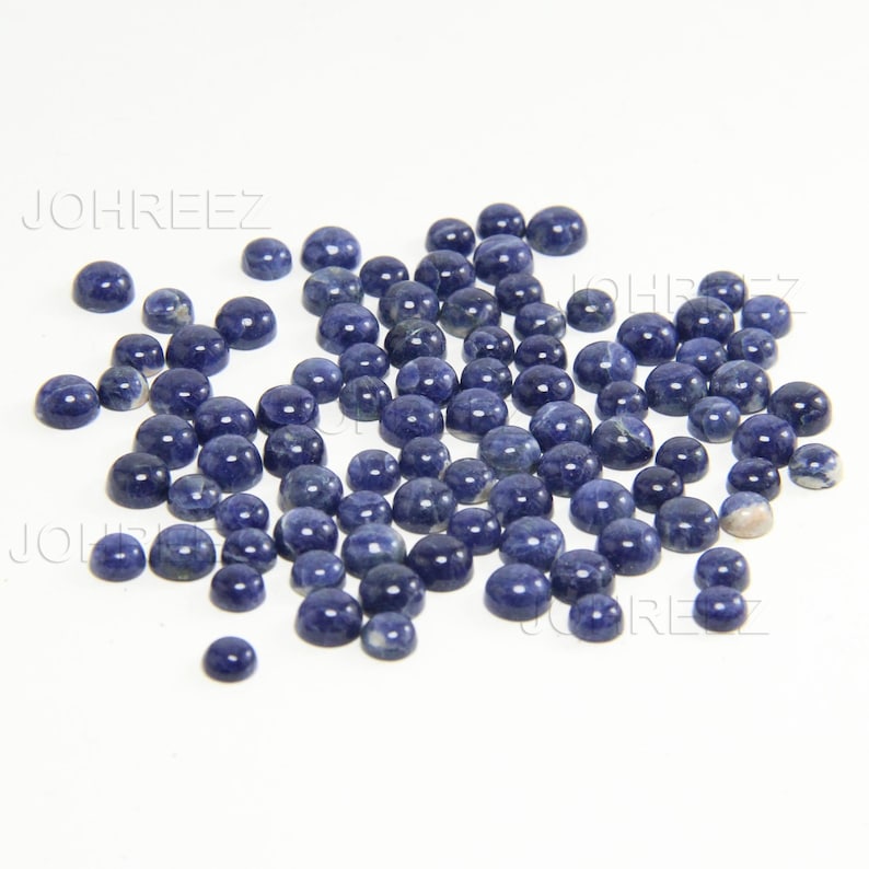 May include: A large group of round, blue-grey gemstone cabochons. The cabochons are smooth and polished, with a slight variation in color and pattern.