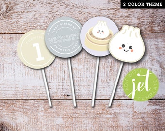 May include: Four round printable cupcake toppers with a light blue, light yellow, and light green color scheme. The toppers feature a number 1, the text "Violet's First Birthday", a cartoon dumpling, and the text "Edit with Jet Template".