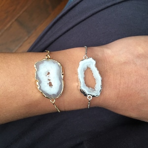 May include: Two agate slice bracelets with gold and silver chain links. The agate slices are white with a clear center.