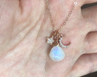 Puede incluir: Un collar de oro rosa con un colgante de piedra lunar, un dije de media luna con piedras transparentes y un dije de estrella con piedras transparentes.