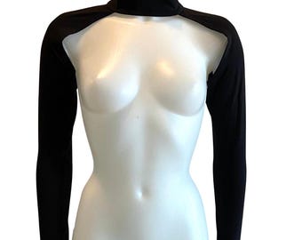 Op de afbeelding: Een zwart bolero-vest met lange mouwen, een hoge opstaande kraag en duimgaten bij de boorden. Het kledingstuk bedekt de schouders en armen terwijl de borst en romp onbedekt blijven, gemaakt van een effen zwarte stof met een gladde afwerking.