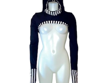 Op de afbeelding: Een zwart bolero-vest met lange mouwen en een aangehechte capuchon met een wit en zwart gestreepte voering. Het kledingstuk is voorzien van bijpassende wit en zwart gestreepte biezen langs de zoom en bij de mouwboorden voor een geheel.