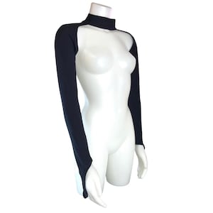 Op de afbeelding: Zwarte shrug met lange mouwen en een hoge halslijn. De shrug heeft duimgaten en wordt getoond op een witte mannequin. Het kledingstuk is gemaakt van een rekbaar materiaal en is ontworpen om de armen en schouders te bedekken.