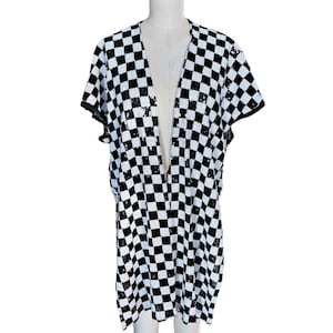 May include: A black and white checkered sequin jacket with short sleeves. The open-front jacket is displayed on a mannequin. The pattern is a classic checkerboard design, with each square being the same size.