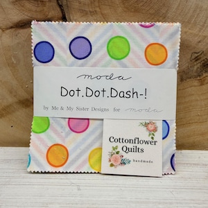 May include: A stack of fabric squares with a white background, colorful polka dots, and diagonal stripes. The fabric is labeled "Dot.Dot.Dash-" by Me & My Sister Designs for Moda. A small tag reads "Cottonflower Quilts handmade."