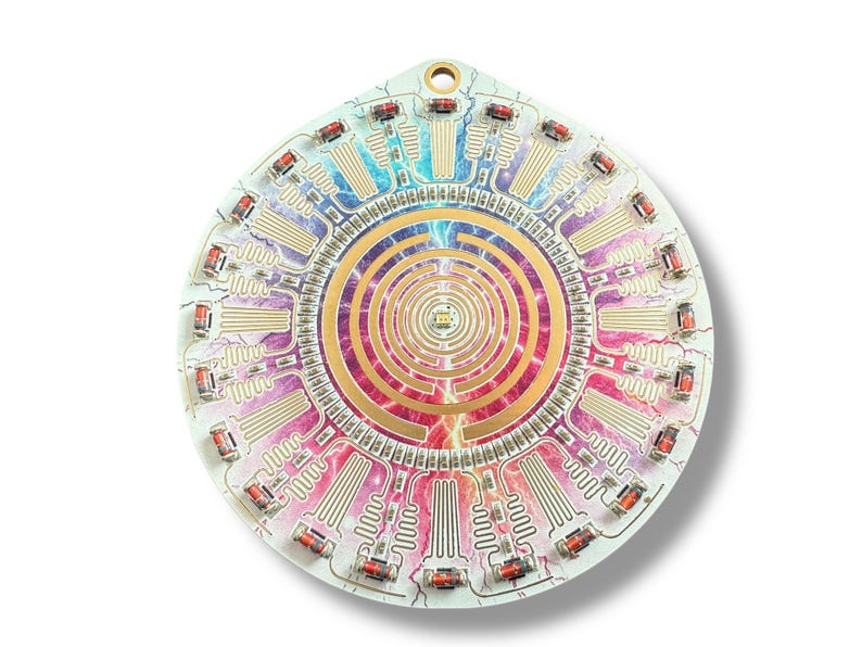 May include: A circular, multi-colored circuit board with a gold-colored, concentric circle pattern in the center. The board has a white background and is decorated with a rainbow of colors. The board is surrounded by a ring of small, red, rectangular components.