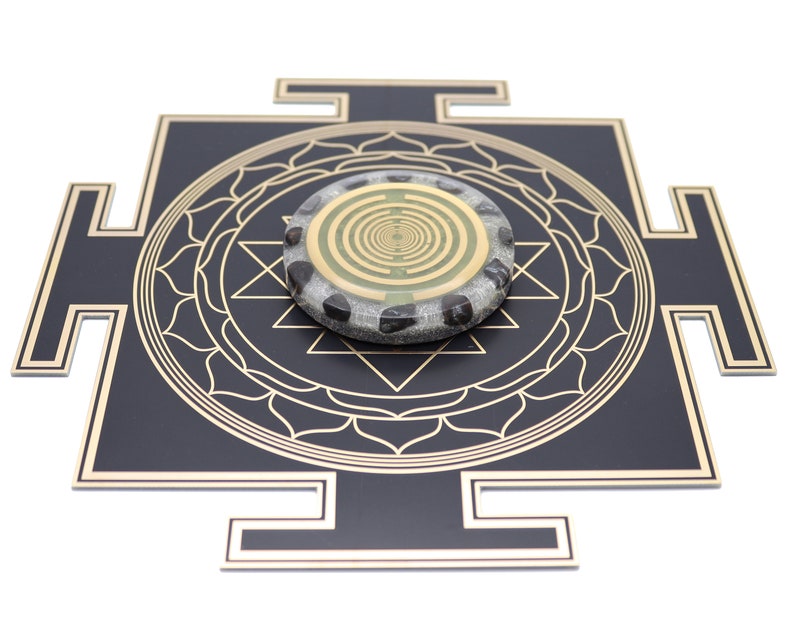 May include: A black and gold geometric design with a circular stone centerpiece. The stone has a gold spiral pattern and is surrounded by black stones. The design is on a white background.