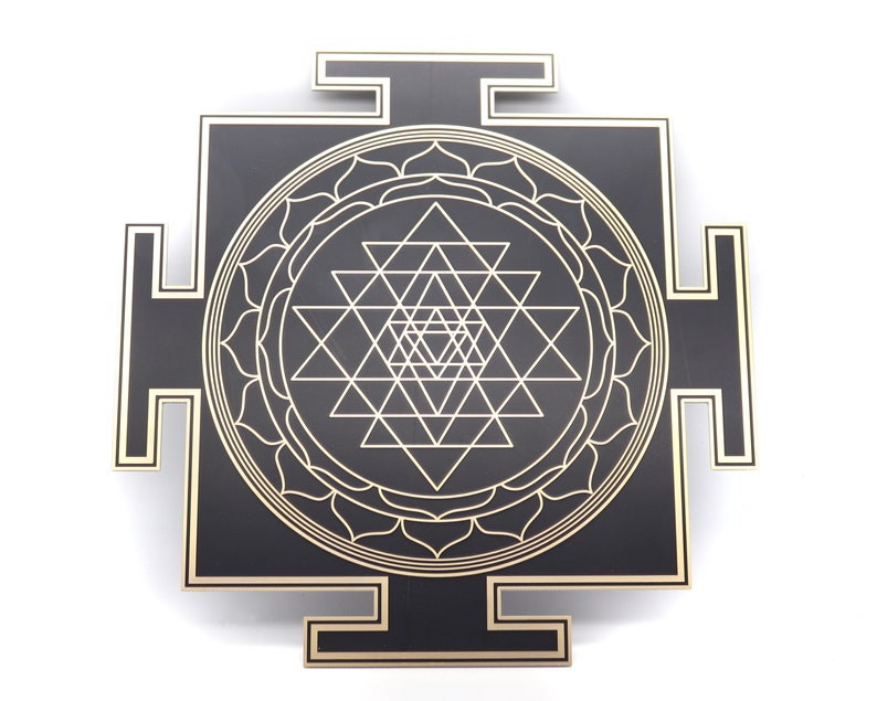 May include: A black and gold Sri Yantra, a geometric design used in Hinduism and Buddhism. The design features interlocking triangles and circles, with a gold outline on a black square. The corners have gold accents.