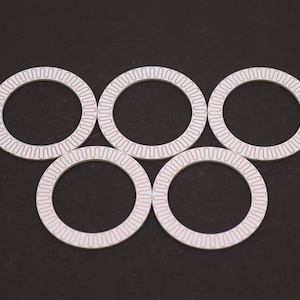 May include: Five white circular rings with a copper-colored pattern around the edge. The rings are arranged in a semi-circle pattern.