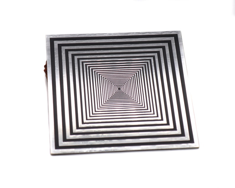 May include: A silver and black square-shaped metal coaster with a concentric square design.