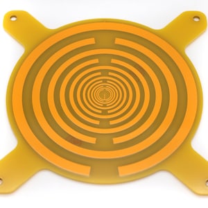 May include: A yellow circular printed circuit board with a concentric circle pattern in orange. The board has four arms extending from the circle, each with a hole at the end.
