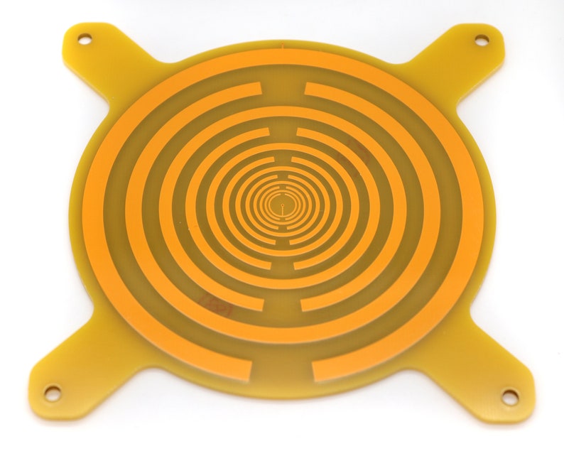 May include: A yellow circular printed circuit board with a concentric circle pattern in orange. The board has four arms extending from the circle, each with a hole at the end.