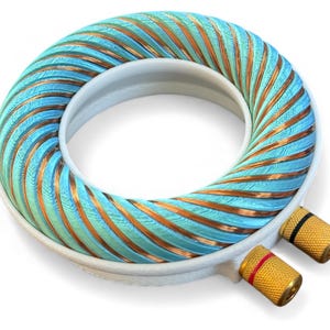 Puede incluir: Un componente de audio circular con un marco blanco, con un diseño en espiral turquesa y cobre. Conectores dorados con detalles rojos y negros están unidos al marco. Componente para equipos de audio.