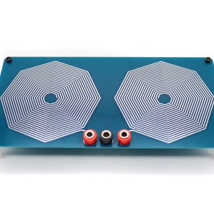 Puede incluir: Una placa de circuito turquesa con dos patrones de bobinas octogonales blancas. La placa tiene terminales rojos y negros y está montada sobre pequeños soportes blancos. Tornillos negros aseguran la placa.