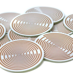 Op de afbeelding: Een close-up van een stapel ronde, witte en bruine printplaten met concentrische cirkels.