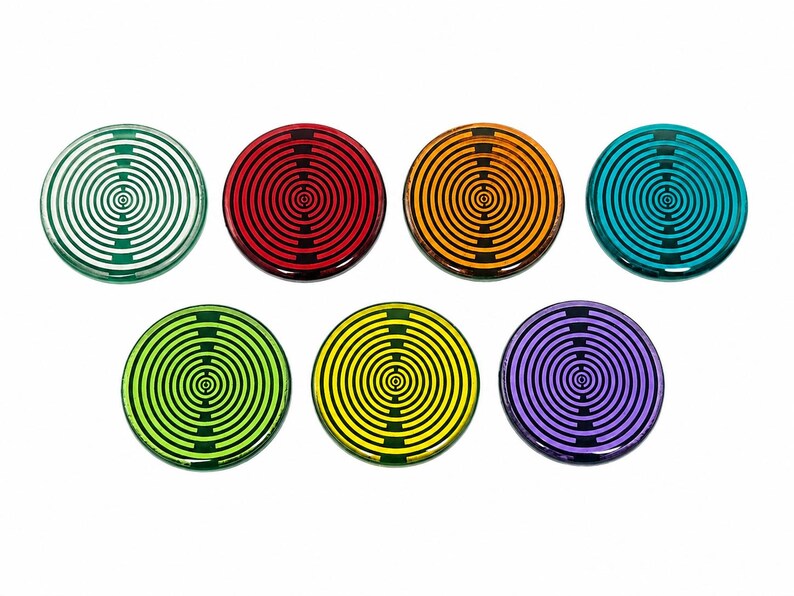 May include: Seven circular coasters in green, red, orange, teal, lime green, yellow, and purple. Each coaster features a black concentric circle pattern with a central dot and two vertical lines intersecting the rings, creating a target-like design.