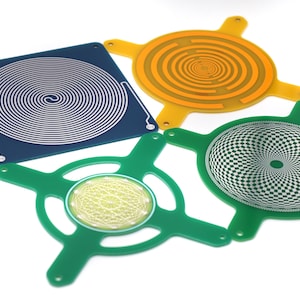 May include: Four different printed circuit boards with various patterns. The boards are green, blue, and orange. The patterns include a spiral, a checkerboard, and a geometric design.