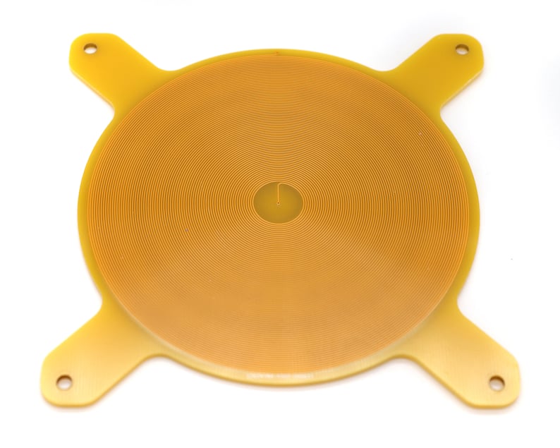 May include: A yellow circular electronic component with a spiral pattern and four arms extending from the edges.