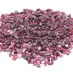 Könnte beinhalten: Ein Haufen kleiner, rotbrauner Granat-Edelsteinchipse. Die Chips sind unregelmäßig geformt und haben eine glänzende Oberfläche.