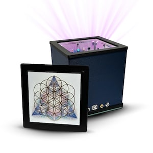 May include: A dark blue, rectangular device with a black top and a glowing purple light emanating from within. A black framed panel displays a geometric design. The device has several ports on the side.