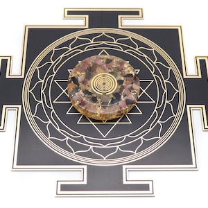 May include: A black and gold geometric design with a central circular object. The circular object is a mix of pink, black, and gold materials. The design features intricate patterns and shapes, creating a visually appealing and spiritual aesthetic.