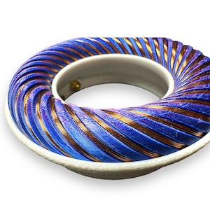 Peut inclure: Gros plan d'une bobine de couleur bleue et cuivre, enroul&eacute;e en spirale. La bobine est mont&eacute;e sur une base blanche.