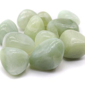 Könnte beinhalten: Eine Sammlung glatter, hellgrüner Jadesteine, die getrommelt und auf Hochglanz poliert wurden.