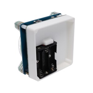 May include: A white plastic case with a blue circuit board inside. The case has a battery compartment on the bottom and a small white button on the front.