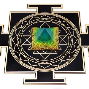 May include: A black and gold geometric wall art piece featuring a central square with a pyramid design in shades of green and gold. The square is surrounded by a gold geometric pattern and a black border.