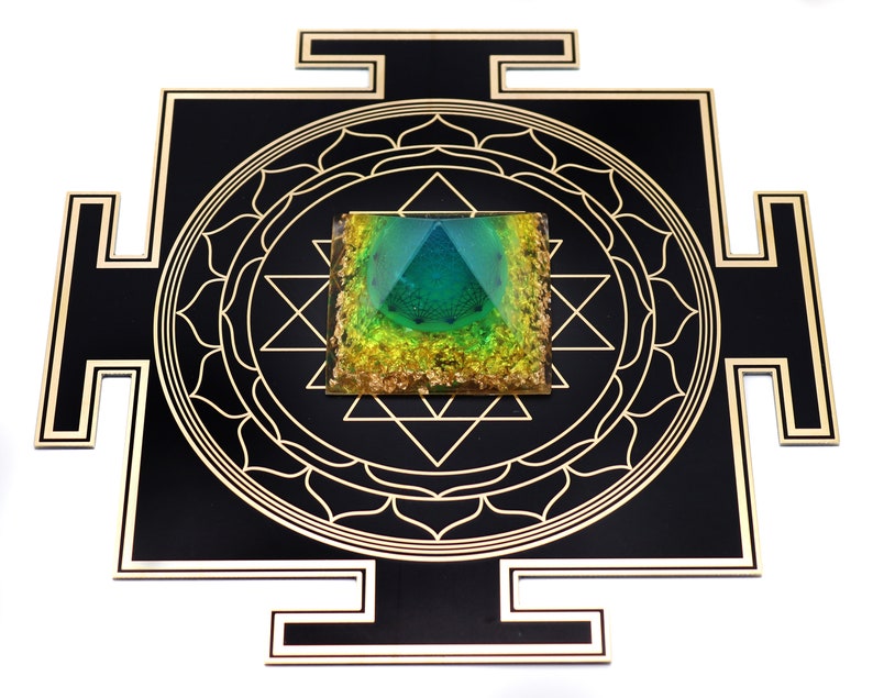 May include: A black and gold geometric wall art piece featuring a central square with a pyramid design in shades of green and gold. The square is surrounded by a gold geometric pattern and a black border.