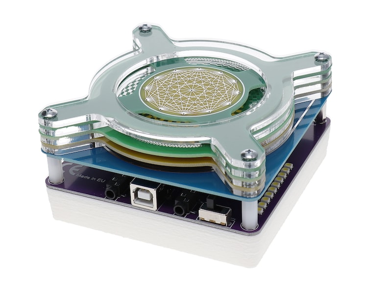 May include: A clear acrylic case with a circuit board and a green and white circular sensor inside. The case has a USB port and two audio jacks. The text "CE made in EU" is visible on the circuit board.