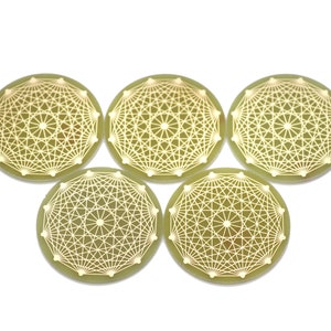 May include: Five round, green coasters with a gold geometric design. The coasters have a raised, circular pattern in the center.