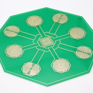 May include: A green octagonal circuit board with eight gold spiral coils arranged in a star pattern.