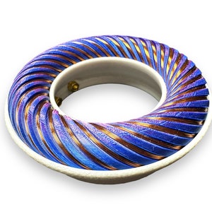 Peut inclure: Une bobine de couleur bleue et cuivre enroul&eacute;e autour d'une base blanche. La bobine est en forme de spirale et a une surface textur&eacute;e.