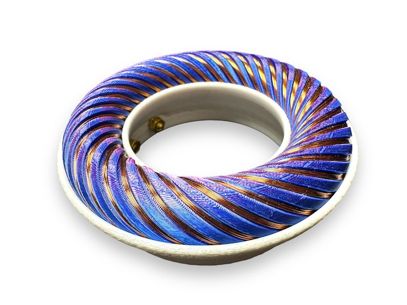 Peut inclure: Une bobine de couleur bleue et cuivre enroul&eacute;e autour d'une base blanche. La bobine est en forme de spirale et a une surface textur&eacute;e.