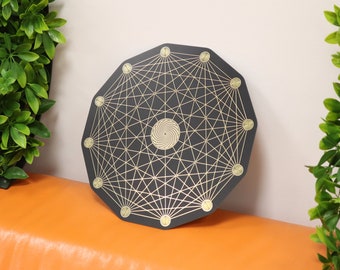 Peut inclure: Une plaque octogonale noire avec un motif géométrique doré et une spirale au centre. La plaque a un bord surélevé et est décorée de points dorés autour du périmètre.