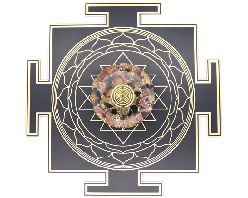 May include: A black and gold geometric wall art piece featuring a central circular design with a spiral pattern. The center circle is filled with a mix of pink, gold, and clear materials. The outer design is a square with a lotus flower and star pattern.